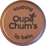 Top view of an engraved Rose Gold aluminium lip balm tin with Oupa Chum’s logo and the words 'soothing' and 'lip balm'